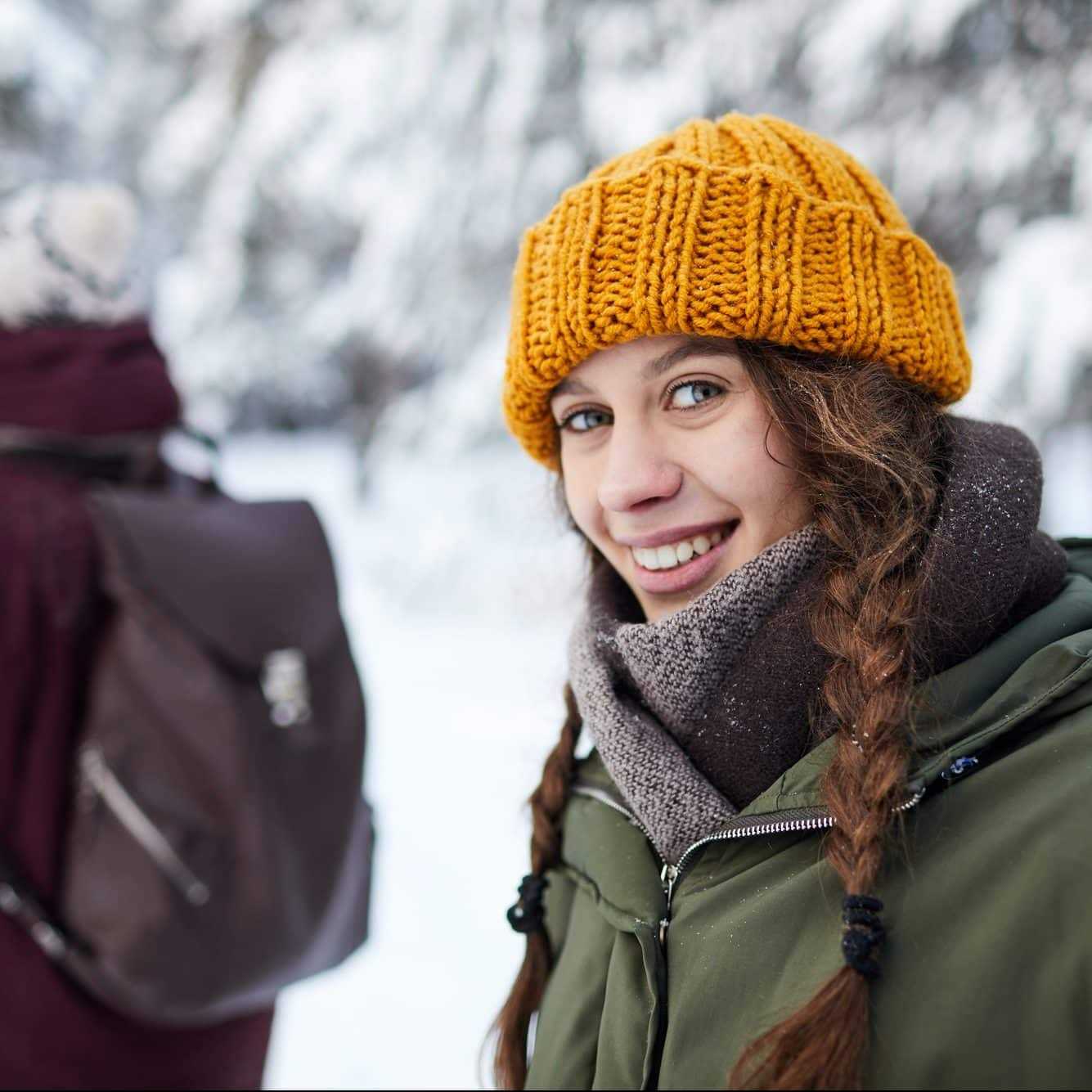 Mädchen lächelt in Kamera in winterlicher Kulisse